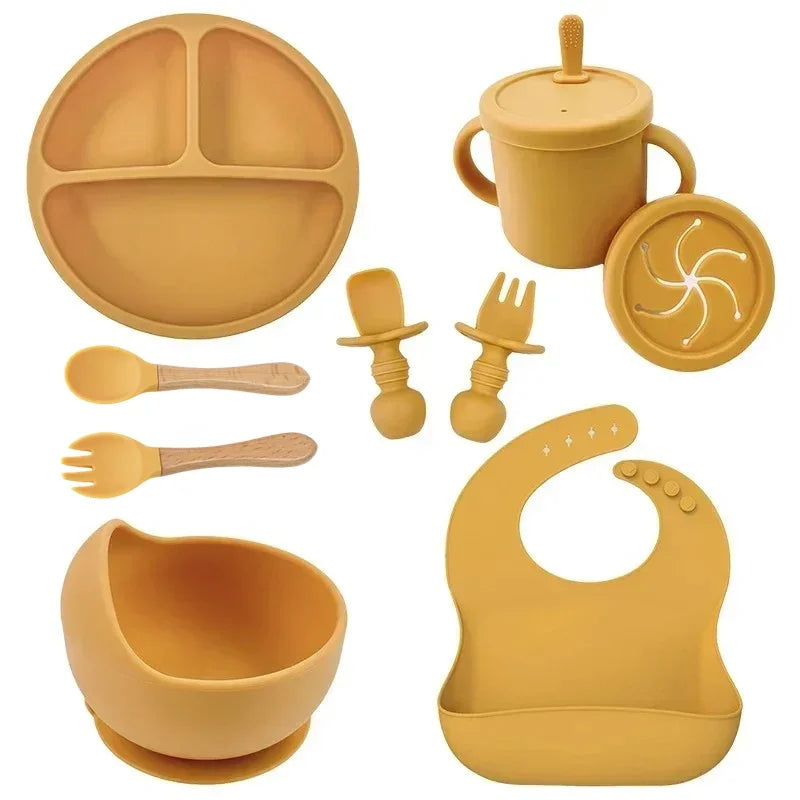 Yellow silicone baby feeding set with divided plate, suction bowl, utensils, cup, and bib