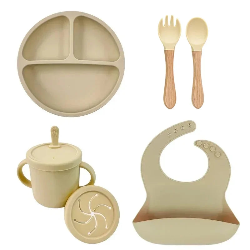 Beige silicone baby feeding set with plate, fork, spoon, cup, and adjustable bib