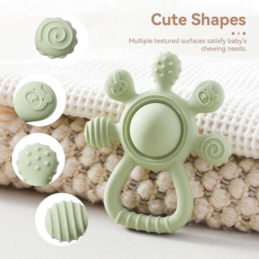 Green baby teether with multiple textured surfaces and cute animal shapes on a soft blanket.