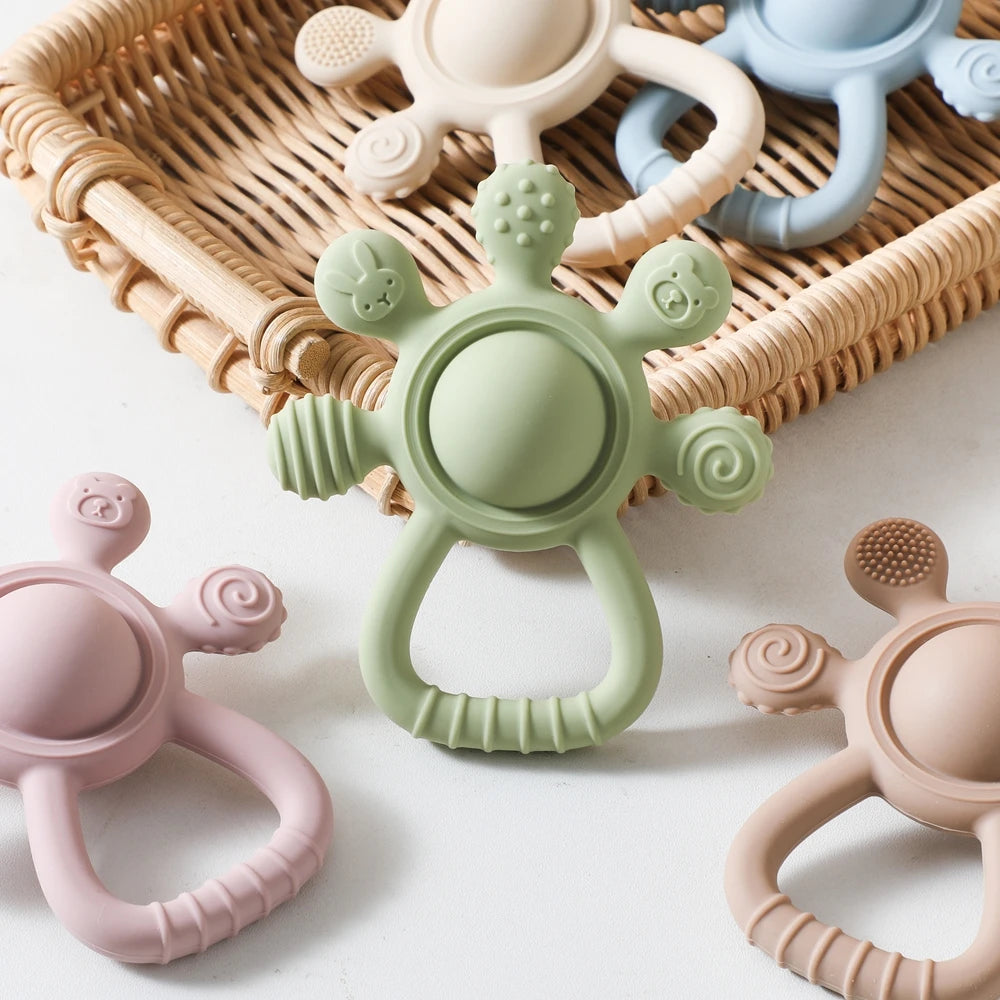 Assorted silicone baby teethers with textured grips in pastel colors on a white surface.