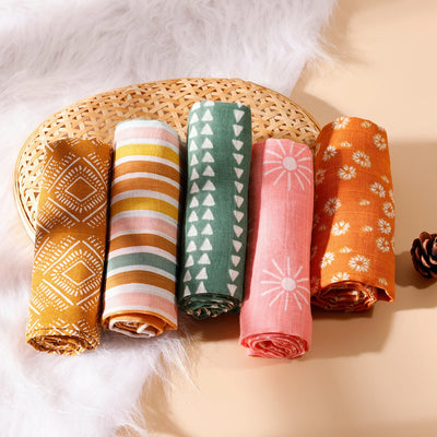 Set of five colorful rolled muslin baby swaddle blankets with geometric and floral prints
