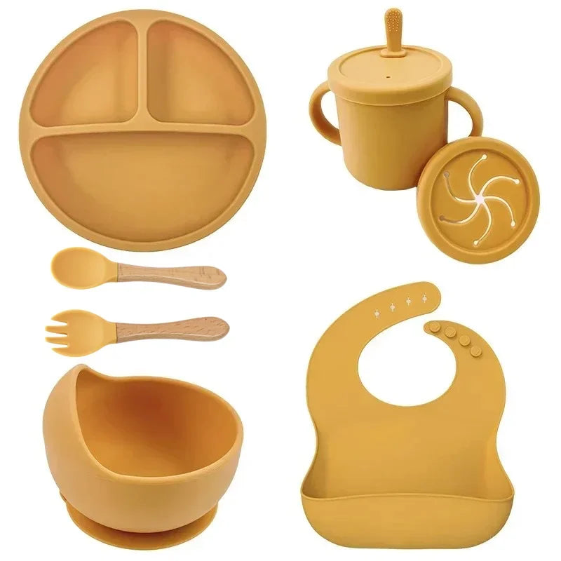 Yellow silicone baby feeding set with bib, divided plate, bowl, sippy cup, spoon and fork.