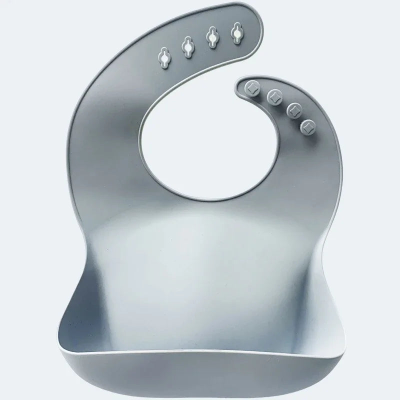 Gray silicone baby bib with adjustable snaps and food catcher pocket on white background