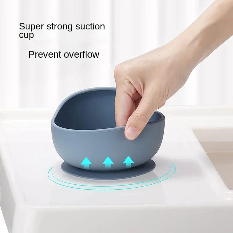 Hand lifting blue silicone suction baby bowl on high chair tray, anti-spill toddler feeding bowl